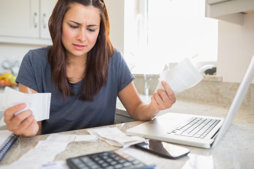Concerned woman paying bills. If you feel overwhelmed with debt and have no way ton pay it back, it might be tie to stat over financially and file for bankruptcy.