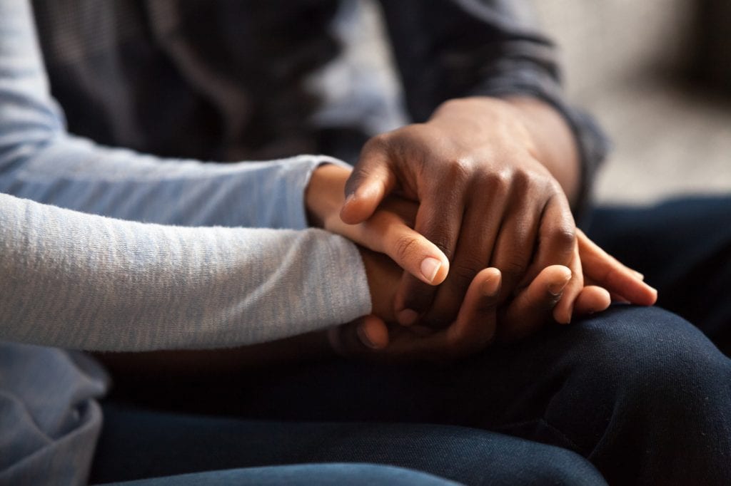 Mother and daughter holding hands following a family death. Without a basic will, your assets may not be distributed as you would wish.