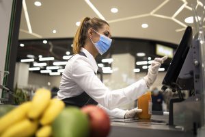 Grocery cashier with protective mask and gloves.